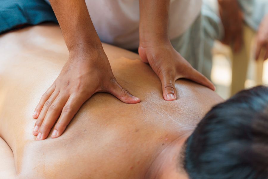 Therapist's hands working on a client's upper back