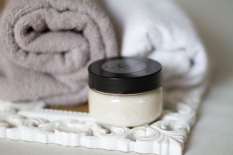 Rolled spa towels beside a jar of body scrub